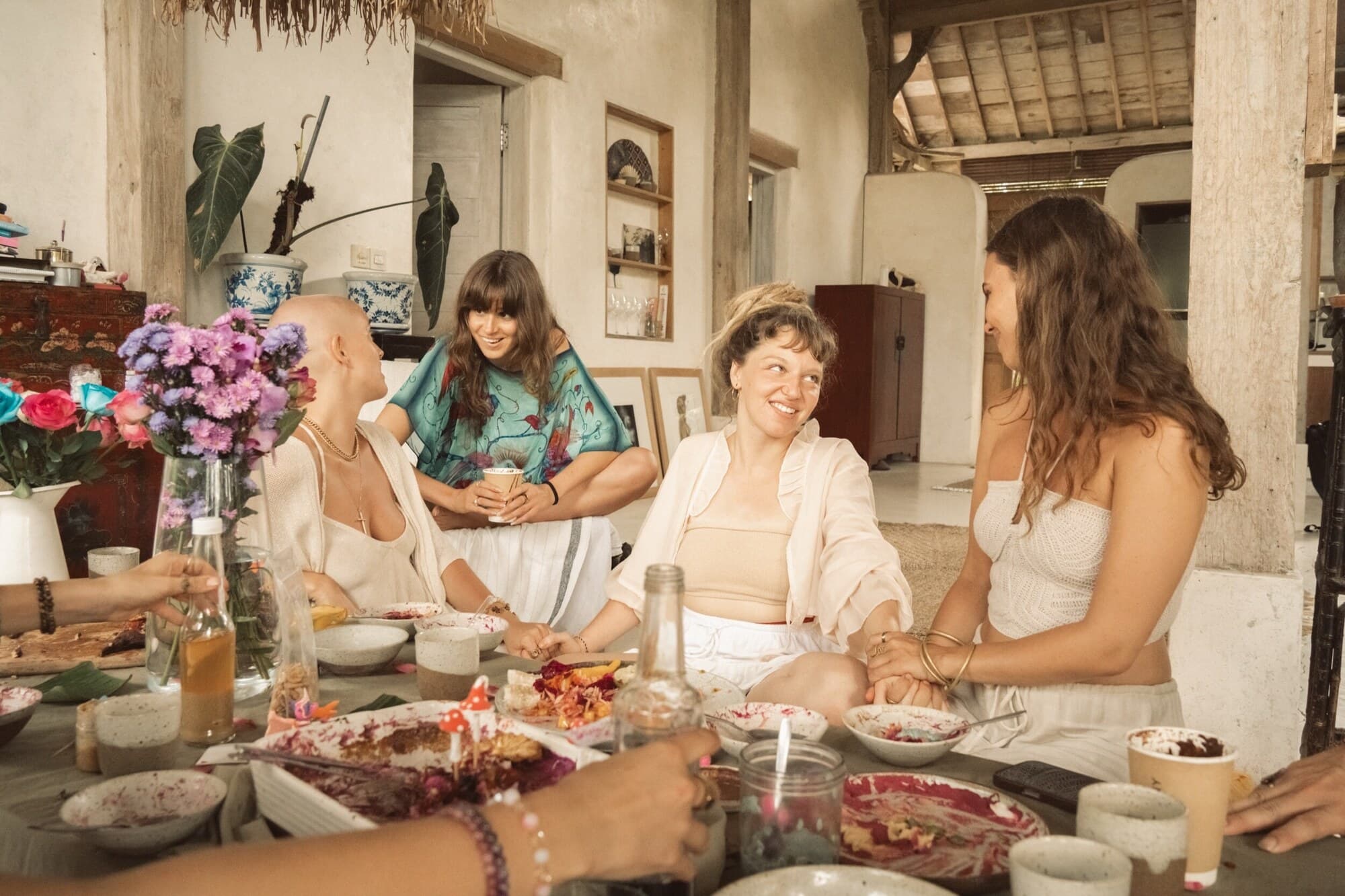 Tribe members laughing together around a table of flowers and shared food in Bali.