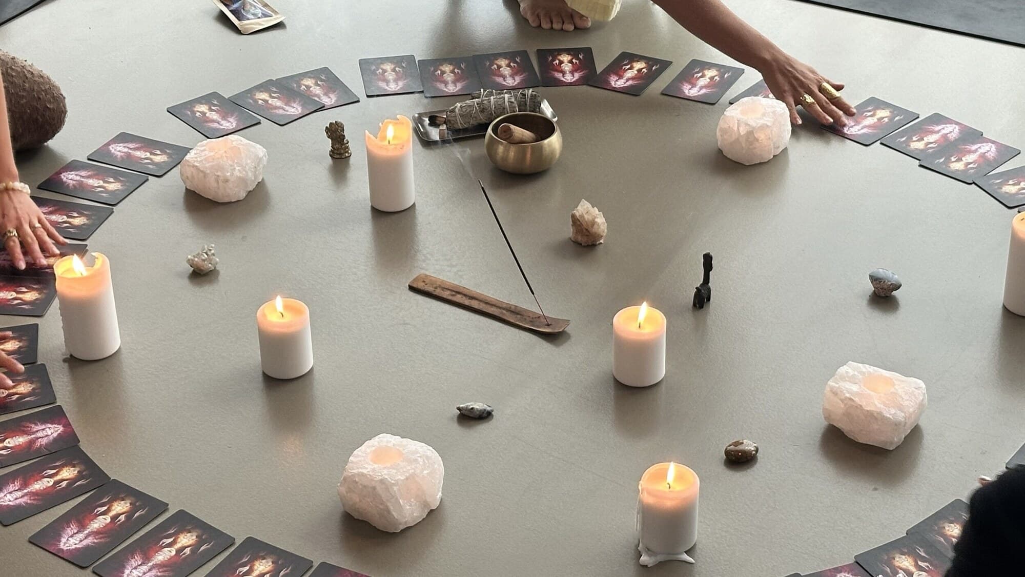 A candlelit mandala of cards, crystals and cacao cups laid out on the floor in Denmark.