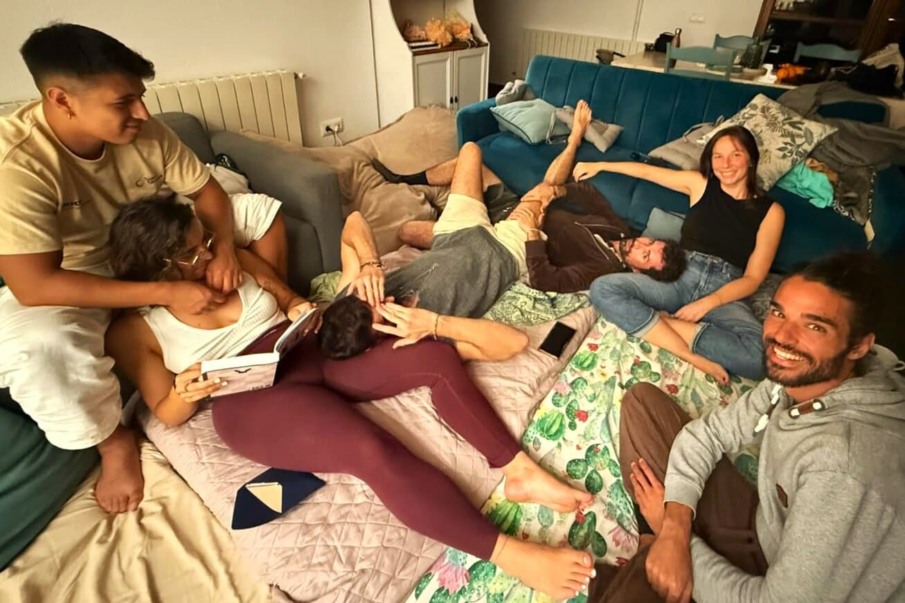 Tribe members resting together on blankets and cushions in a living room in Spain.